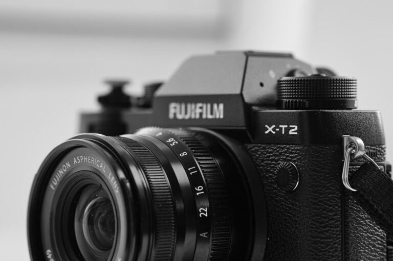 A close-up of a Fujifilm X-T series camera, focusing on its retro-style control dials and textured body.